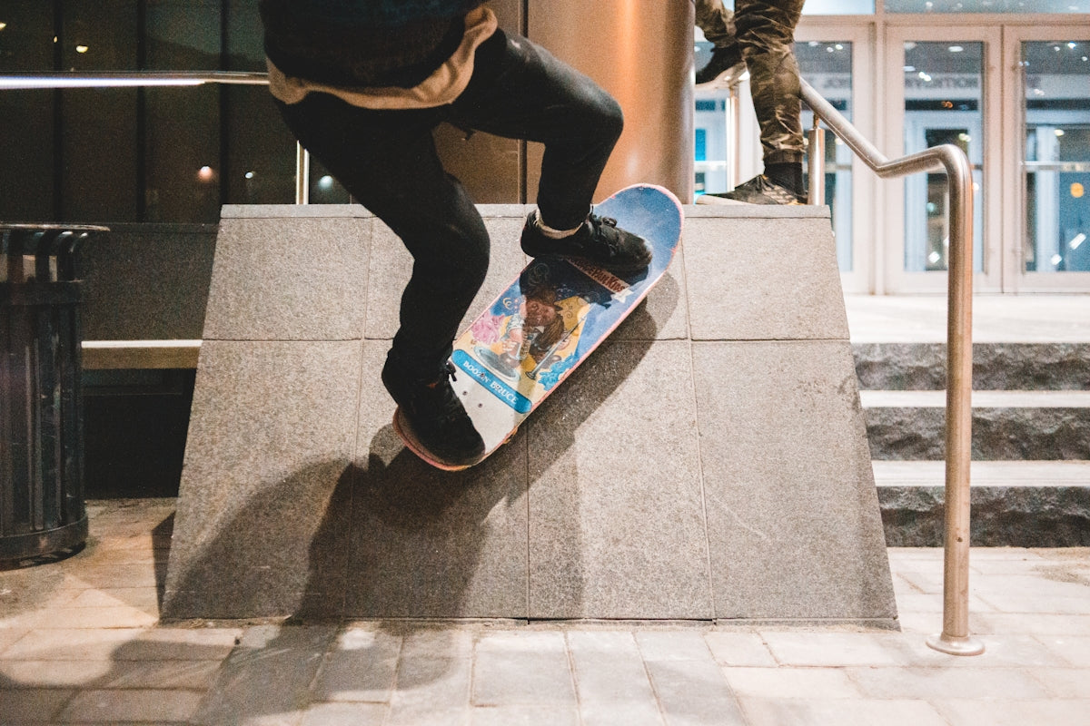 person in black jacket and blue denim jeans sitting on concrete bench