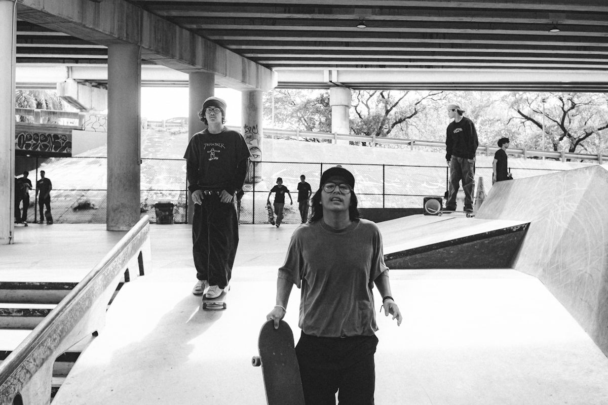 a man holding a skateboard while standing in a skate park