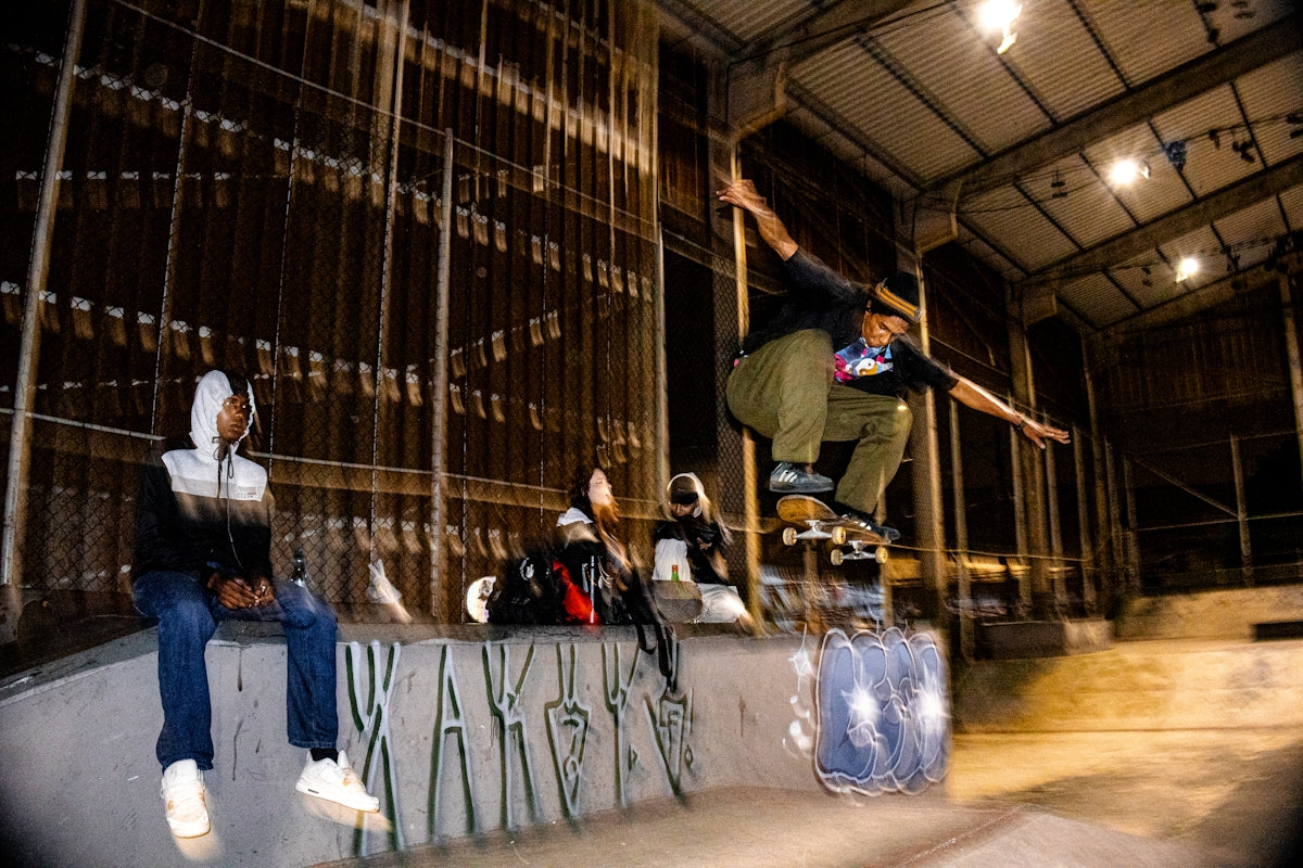 Skateboarder performing a trick in an indoor skatepark.