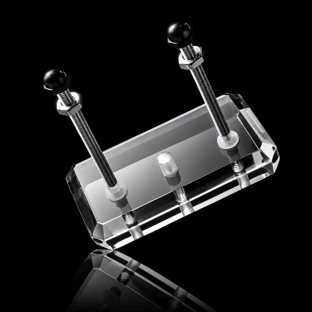 Clear acrylic skateboard wall mount block with two upright steel rods and black cap nuts on a black background