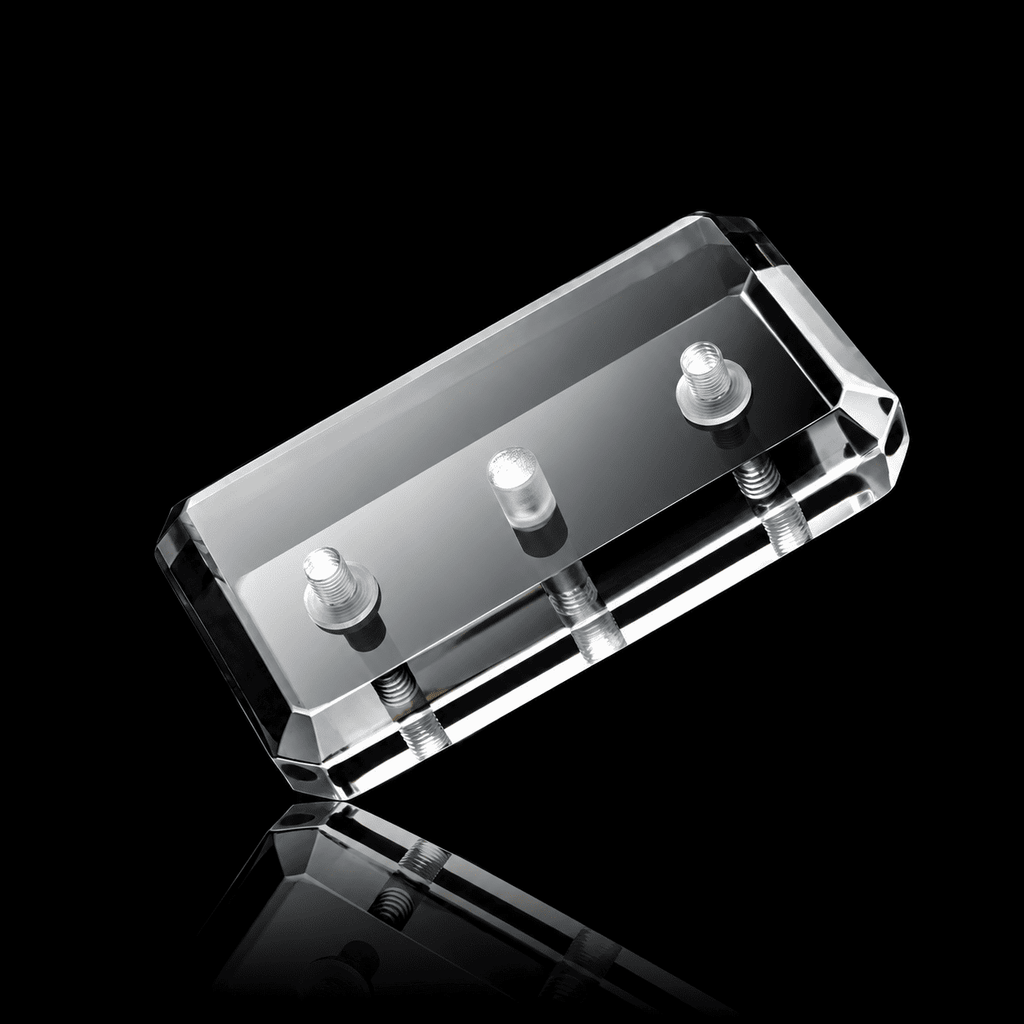 Beveled clear acrylic skateboard wall mount block with three small studs on its face, shown on a black background